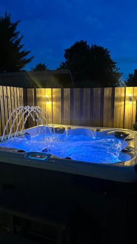 a hot tub with blue water in front of a fence at Entire Cotswolds barn retreat in Carterton