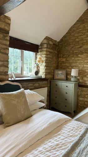 a bedroom with a bed and a dresser and a window at Entire Cotswolds barn retreat in Carterton