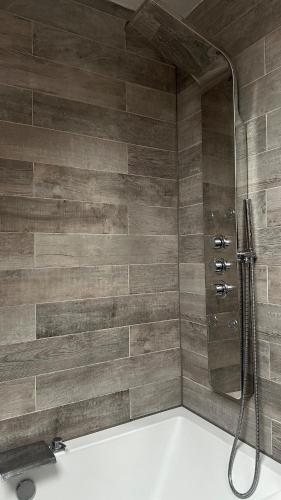 a shower with a hose in a bathroom at Entire Cotswolds barn retreat in Carterton