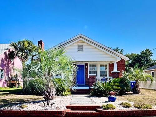 a house with a blue door and palm trees at CB Sunshine Cottage in Carolina Beach