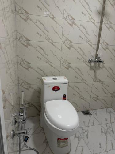 a white toilet in a bathroom with marble walls at Jasmin in Ganja