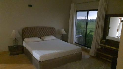 a bedroom with a bed and a large window at A Friendly Family Home in Lahore