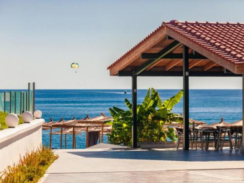 a pavilion with tables and chairs and the ocean at Blue Sea Island in Kolimbia
