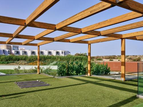 a wooden pergola in a yard with green grass at Blue Sea Island in Kolimbia