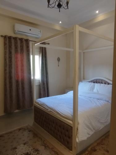 a bedroom with a canopy bed with white sheets at Laguna King - care & comfort in Naj‘ al Aḩwāl