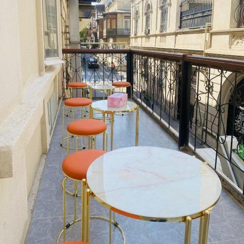 eine Reihe von Tischen und Hockern auf einem Balkon in der Unterkunft Camden Hostel in Baku