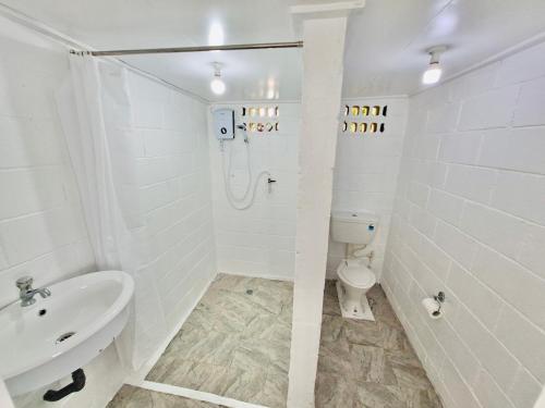 a white bathroom with a sink and a toilet at Tonga Village - Entire Compound with 4 Cottages Large Groups in Nuku‘alofa