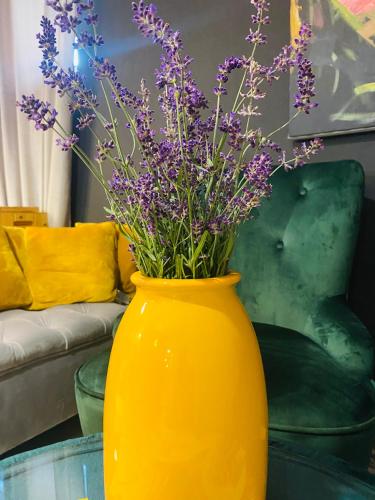 a yellow vase filled with purple flowers on a table at Rooms & Apartment ZALA in Cerklje na Gorenjskem