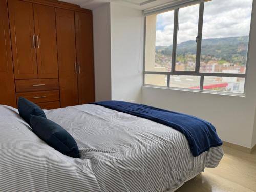 a bedroom with a bed with a blue blanket on it at Comodo Apartamento con Terraza Privada in Sogamoso