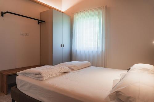 a bedroom with a bed with white sheets and a window at Casa Stefania 1 in Pieve Di Ledro