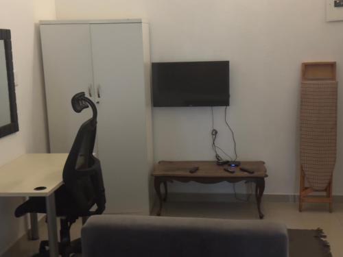 a living room with a desk and a tv and a table at Airport Guest House in Kempton Park