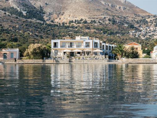 a large house on the shore of a body of water at Pedi Beach Hotel in Symi