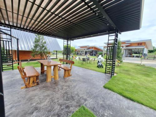 a pavilion with a picnic table and benches under awning at บ้านน้ำผึ้งโฮมสเตย์ in Suan Phung