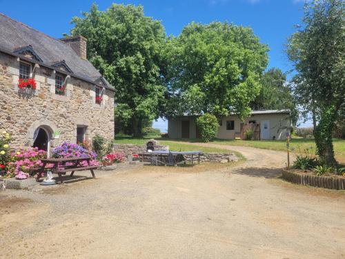 a stone building with picnic tables and flowers in front of it at Maisonnette bretonne in Quemper-Guézennec