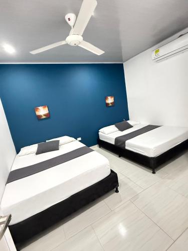 two beds in a room with a blue wall at TORRES DEL MESÓN LUXURY APARTA HOTEL Doradal in Doradal