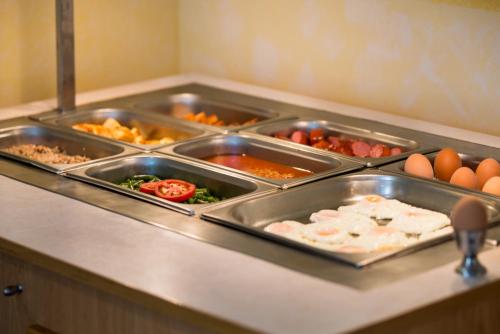 una linea di buffet con molti vassoi di cibo e uova di Atlant Hotel a Sveti Konstantin i Elena