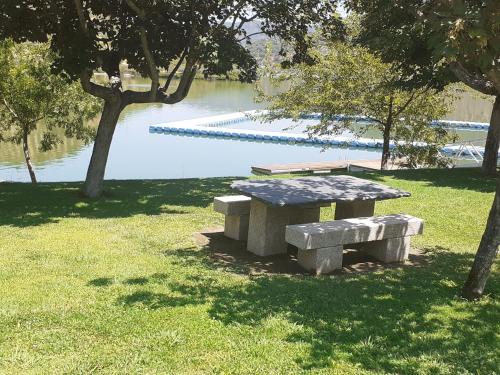a picnic table and bench in front of a lake at Casa das Eiras in Mazouco