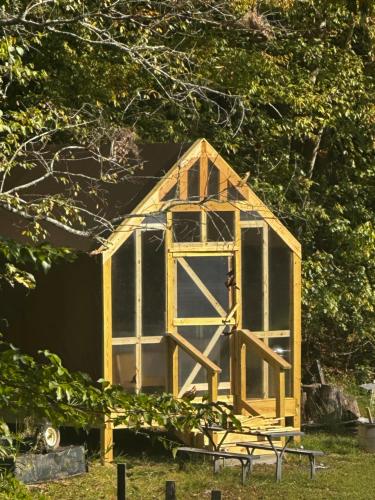 a yellow chicken coop with a door in the grass at Luxury Cozy Glamping Cabin Retreat Natural Hide Out in Sugar Hill