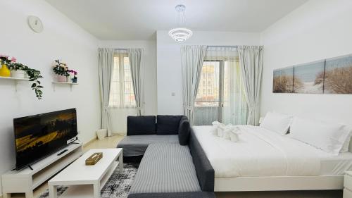 a white living room with a large bed and a tv at X11 Furnished with balcony England cluster international city near Dragon Mart in Dubai