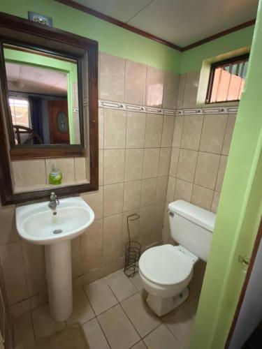 Un baño con inodoro, lavabo y espejo. en Casa VASBA, en Golfito