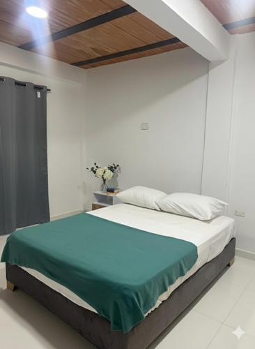 a white bedroom with a bed with a green blanket at Casa Mariana Hostel Boutique in Santa Marta