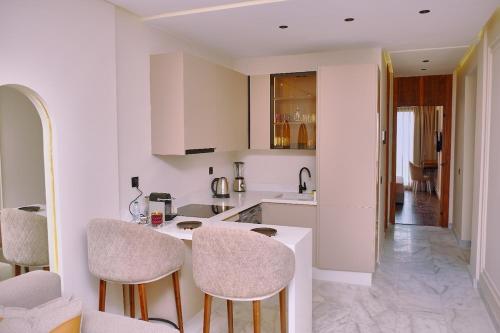 a kitchen with white cabinets and bar stools at Pied-à-terre Moderne & Confortable à Casa in Casablanca