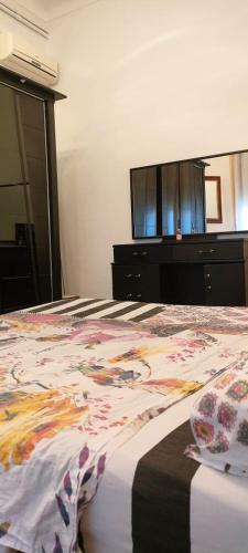 a bedroom with a bed with a dresser and a television at Le Havre de joie in Alger