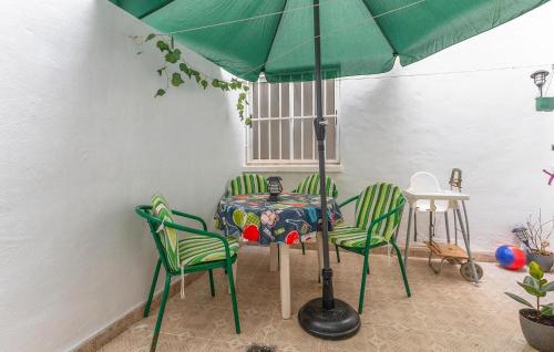 a table with two chairs and a green umbrella at Awesome Apartment In Torrevieja With Wifi in Torrevieja