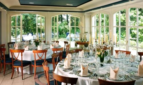 ein Esszimmer mit Tischen und Stühlen und Fenstern in der Unterkunft Waldhaus an de Miälkwellen in Ladbergen