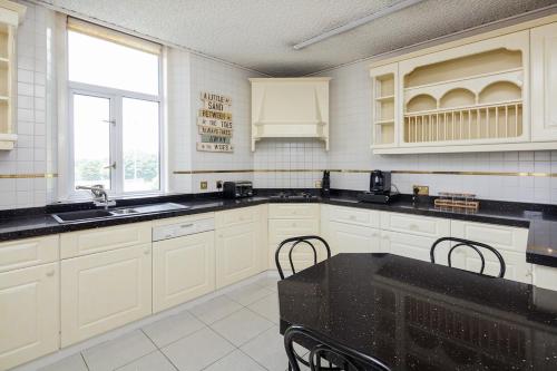 a kitchen with white cabinets and a black counter top at Beautiful 'Mayfield' Villa with private pool! in Manchester