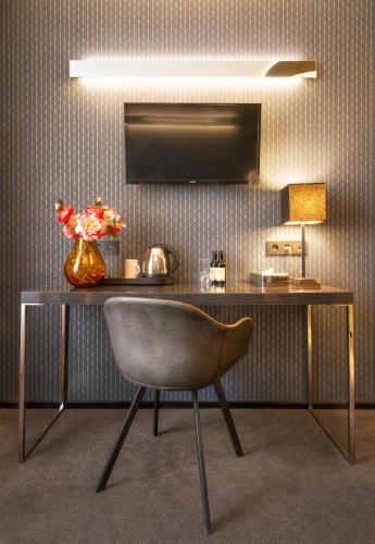a desk with a chair and a vase of flowers at Hotel Mucha in Prague