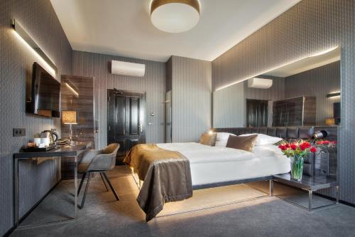 a bedroom with a large white bed and a desk at Hotel Mucha in Prague