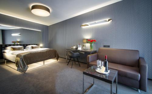 a bedroom with a bed and a couch and a table at Hotel Mucha in Prague