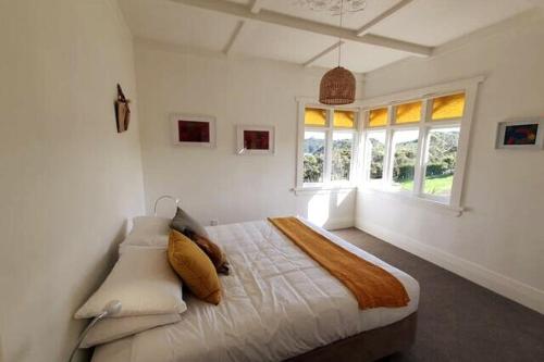 a bedroom with a large bed in a room with windows at The Cottage on the Olive Grove in Russell