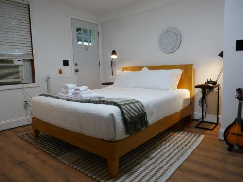 a bedroom with a bed with white sheets and a guitar at 10 Minute walk to Light Rail in Jersey City