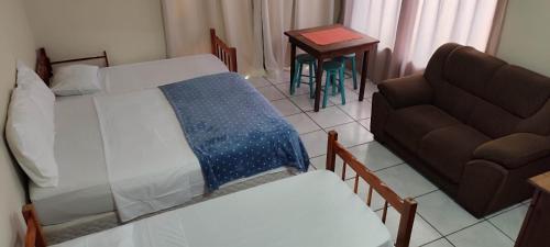 a bedroom with a bed and a couch and a table at Margarida pousada in Garopaba
