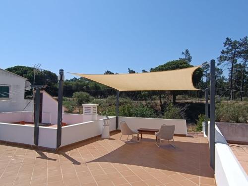a patio with a tan umbrella and chairs and a table at Casa do Poço in Vila Real de Santo António