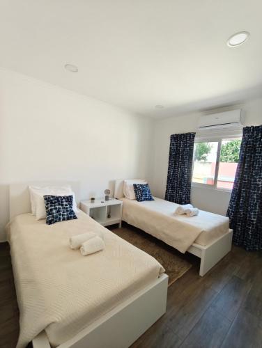 a bedroom with two beds and a window at Casa do Poço in Vila Real de Santo António