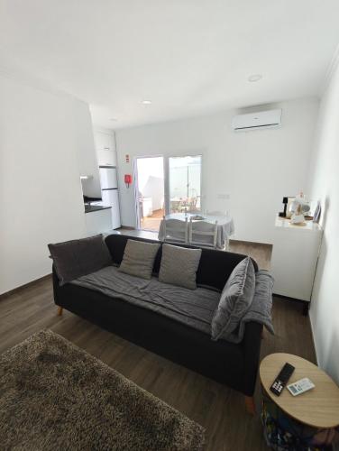 a living room with a black couch and a kitchen at Casa do Poço in Vila Real de Santo António