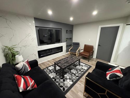 a living room with a black couch and a fireplace at Cozy 3-Bedroom Basement Suite with Private Entrance in Winnipeg
