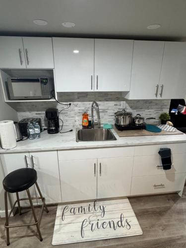 a kitchen with white cabinets and a sink and a kitchen rug at Cozy 3-Bedroom Basement Suite with Private Entrance in Winnipeg