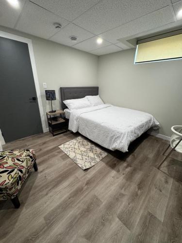 a bedroom with a bed and a chair in it at Cozy 3-Bedroom Basement Suite with Private Entrance in Winnipeg