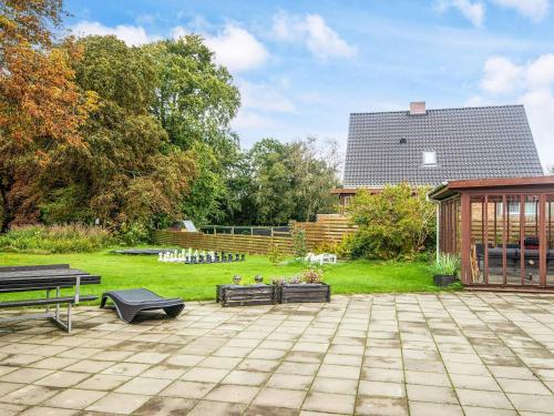 a patio with benches and a building in a yard at 4 star holiday home in Nørre Nebel in Nørre Nebel