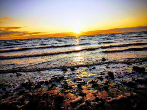 a sunset on the beach with the ocean at 4 person holiday home in Thisted-By Traum in Thisted