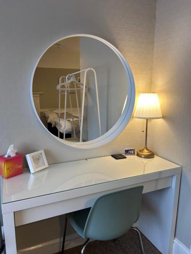 a mirror above a desk with a chair and a lamp at The Lethbridge Arms in Taunton