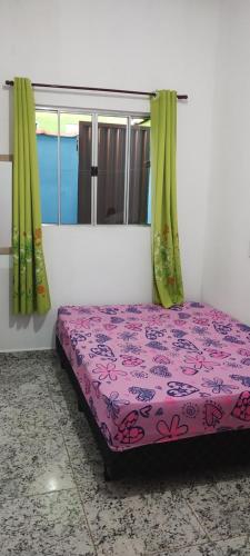 une chambre avec un lit violet avec des rideaux verts dans l'établissement Kit net stl, à São Thomé das Letras