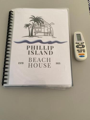 a notebook with a beach house and a remote control at Phillip Island Central Cowes Pet Friendly Wifi Linen Towels Included Beach House in Cowes