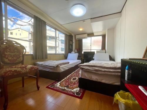 ein Schlafzimmer mit zwei Betten, einem Stuhl und einem Fenster in der Unterkunft Atami Hotel 101 in Atami