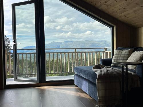 een woonkamer met een bank en een groot raam bij Modern and cozy mountain cabin - panoramic view! in Torvetjørn