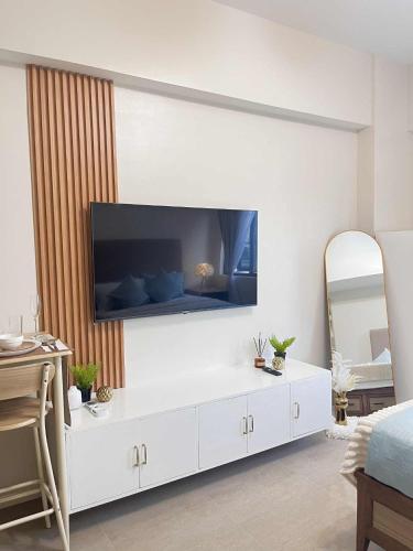 a white living room with a tv on a wall at ARA Condotel in Cebu City